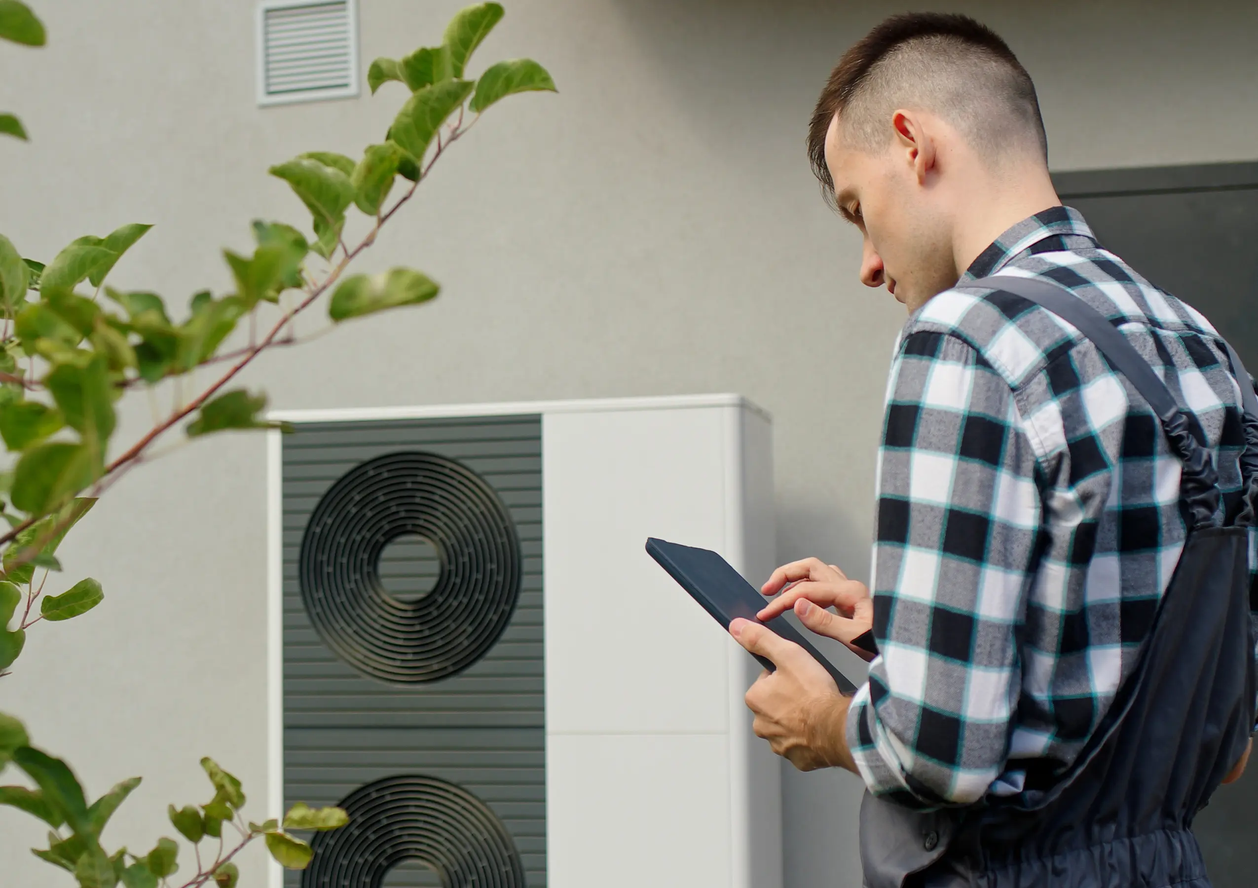 Un installateur inspectant une pompte à chaleur